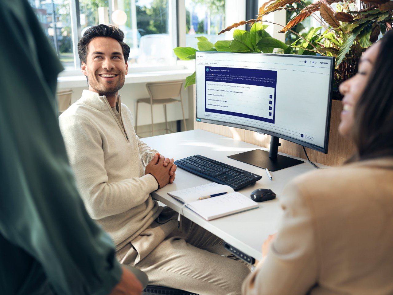 Person sitting at a desk with a computer monitor displaying an online form, surrounded by colleagues.