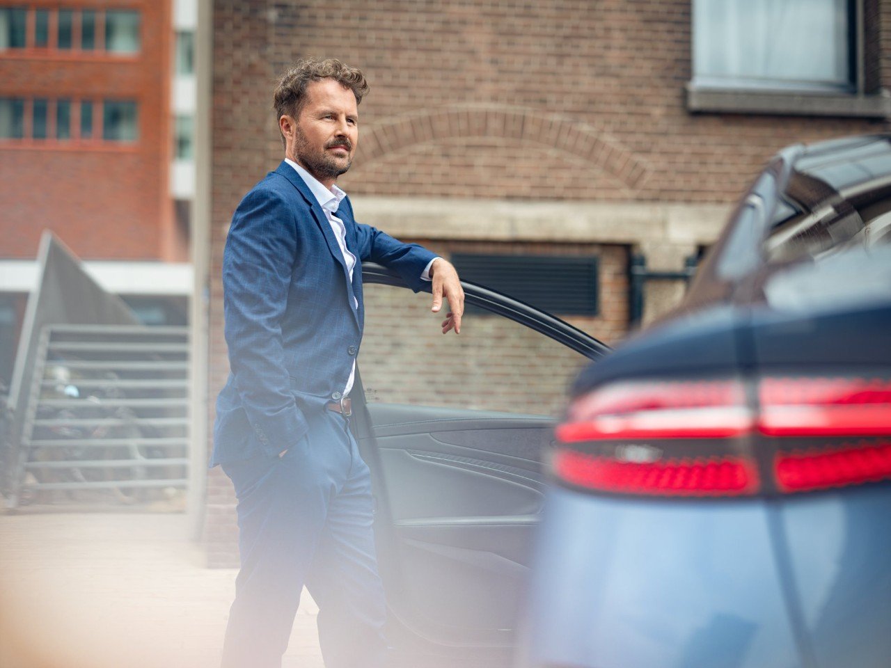Man rests his arm on the driver’s door of a car.